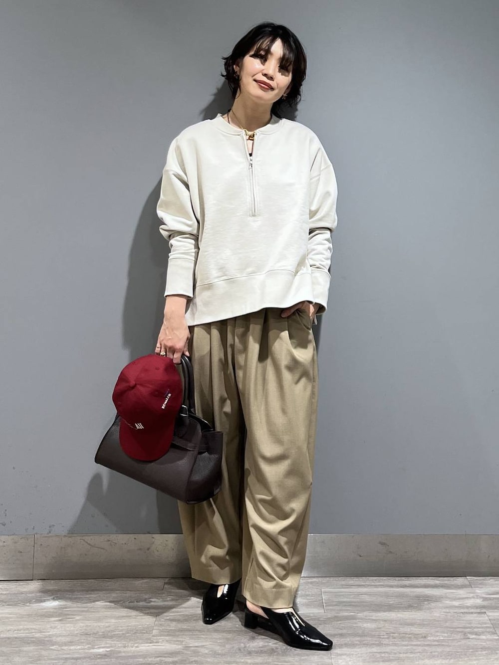 ベージュ系のスラックス、ブラック系のパンプス、ブラウン系のショルダーバッグを着用したレディースの冬コーディネートの1枚目の写真