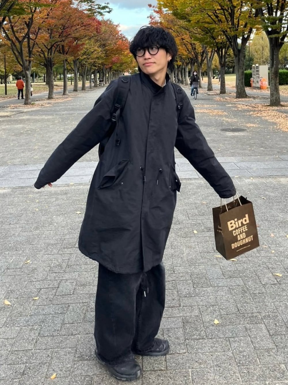 ブラック系のモッズコート、ブラック系のスニーカー、ブラック系のメガネを着用したメンズの秋コーディネートの1枚目の写真