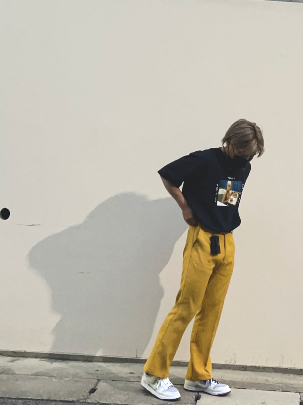 イエロー系のスラックス、ホワイト系のスニーカー、ブラック系のTシャツ/カットソーを着用したメンズの春コーディネートの1枚目の写真