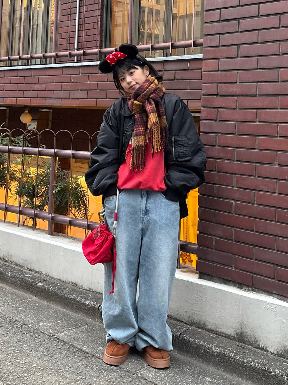 レッド系のスウェット、ブルー系のデニムパンツ、レッド系のショルダーバッグを着用したレディースの秋コーディネートの1枚目の写真