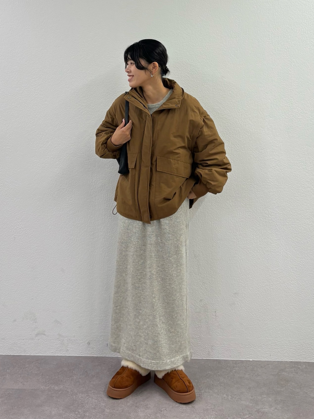 ブラウン系のブルゾン、ブラウン系のサンダル、イエロー系のハンドバッグを着用したレディースの秋コーディネートの1枚目の写真