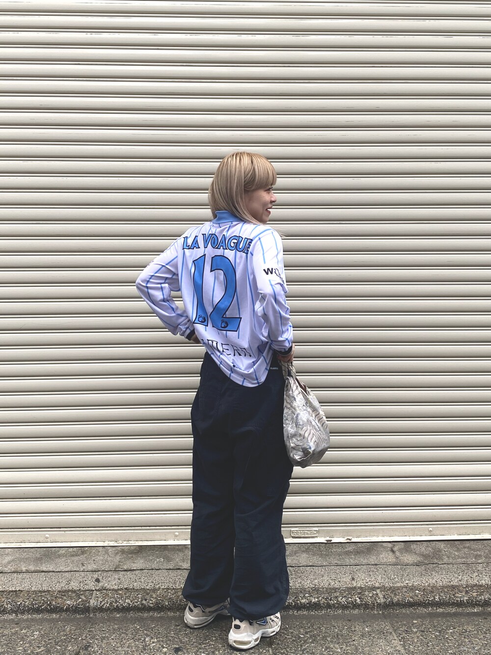 ブラック系のカーゴパンツ、ベージュ系のスニーカー、シルバー系のトートバッグを着用したレディースの春コーディネートの1枚目の写真