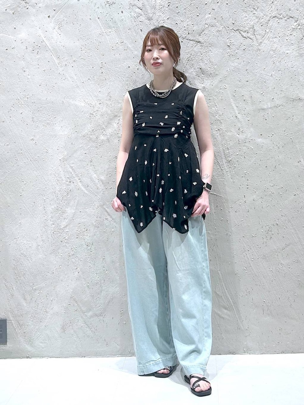 ブラック系のタンクトップ、ブラック系のサンダル、ブルー系のデニムパンツを着用したレディースの秋コーディネートの1枚目の写真