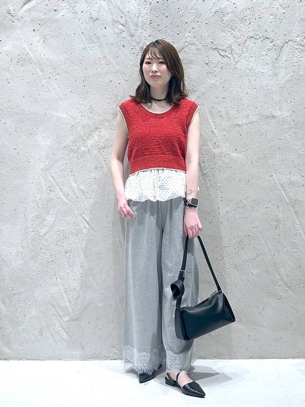 レッド系のベスト、ブラック系のサンダル、ブラック系のショルダーバッグを着用したレディースの夏コーディネートの1枚目の写真