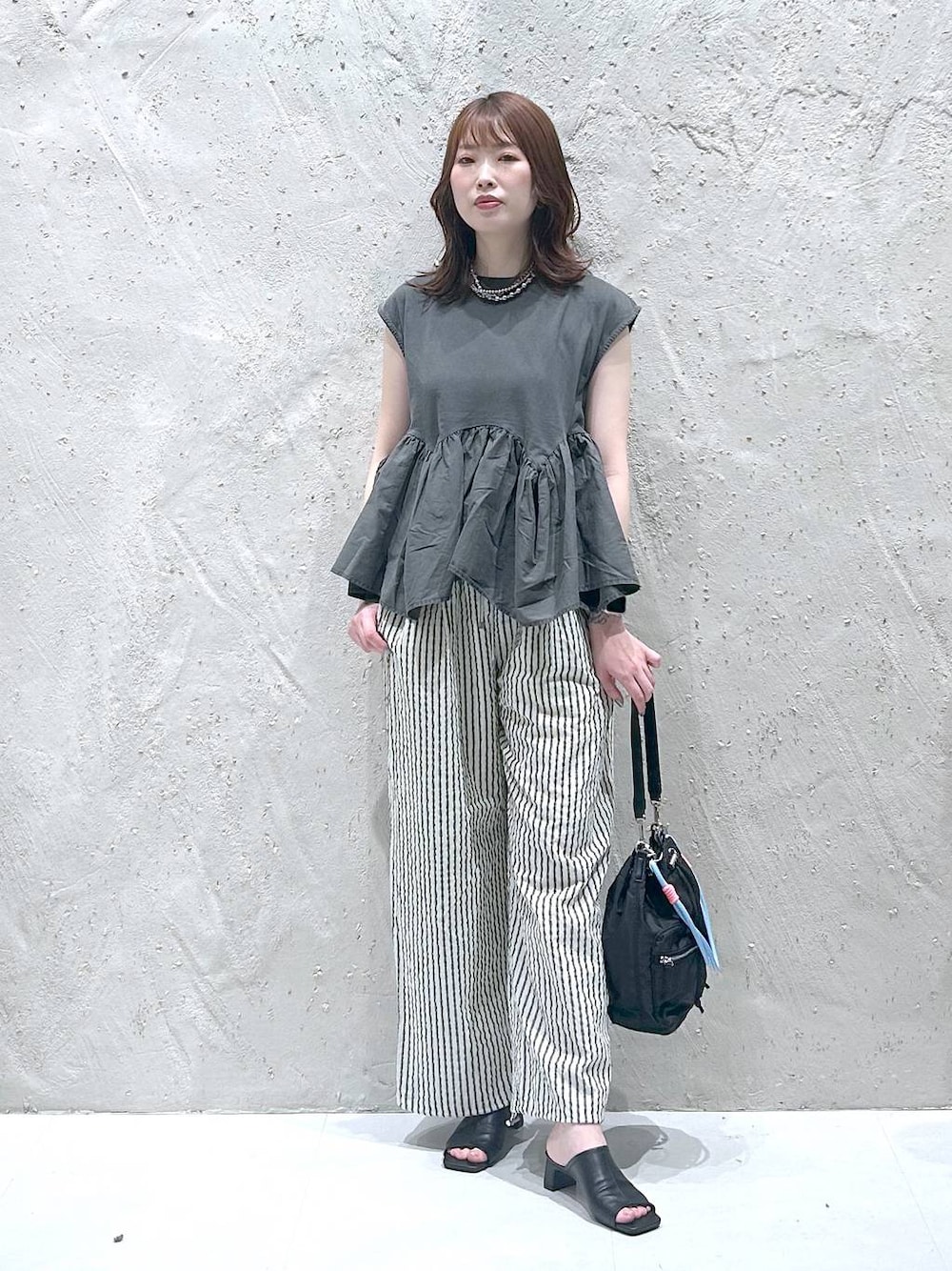 グレー系のTシャツ/カットソー、ブラック系のサンダル、ブラック系のショルダーバッグを着用したレディースの秋コーディネートの1枚目の写真