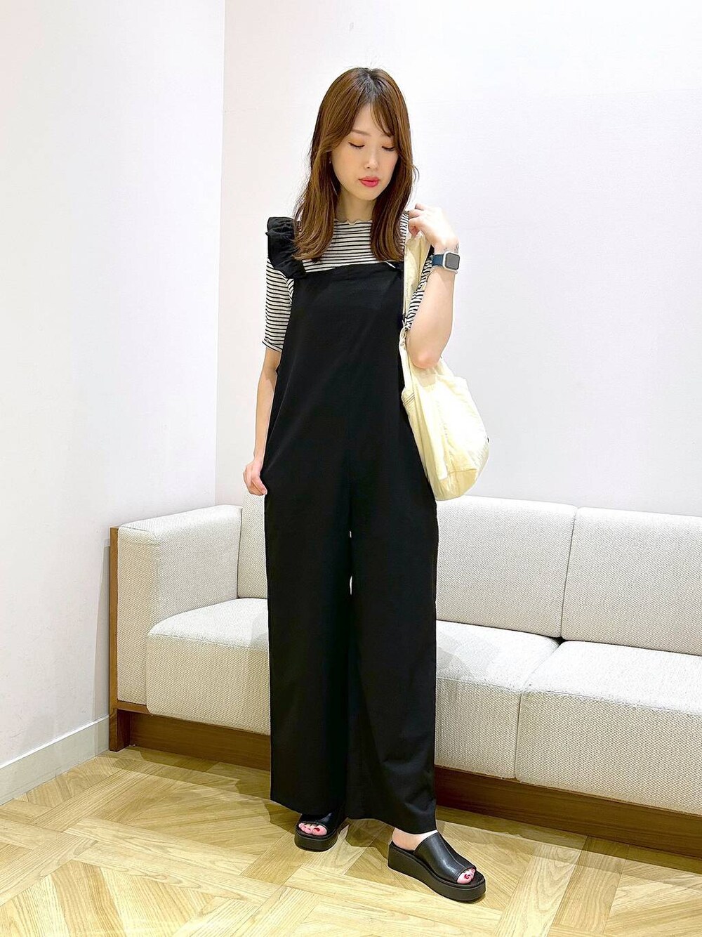 ホワイト系のショルダーバッグ、ブラック系のサンダル、ホワイト系のTシャツ/カットソーを着用したレディースの夏コーディネートの1枚目の写真