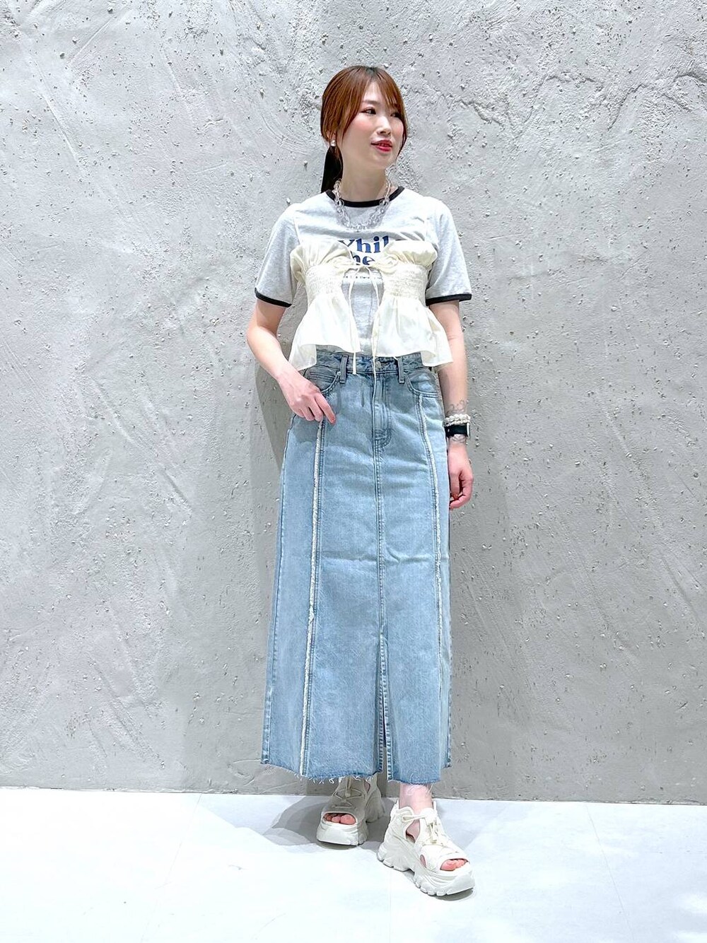 ブラック系のサンダル、グレー系のTシャツ/カットソー、ブルー系のスカートを着用したレディースの春コーディネートの1枚目の写真