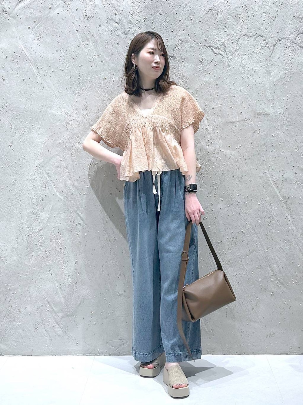 ブルー系のデニムパンツ、ホワイト系のサンダル、ブラウン系のショルダーバッグを着用したレディースの夏コーディネートの1枚目の写真