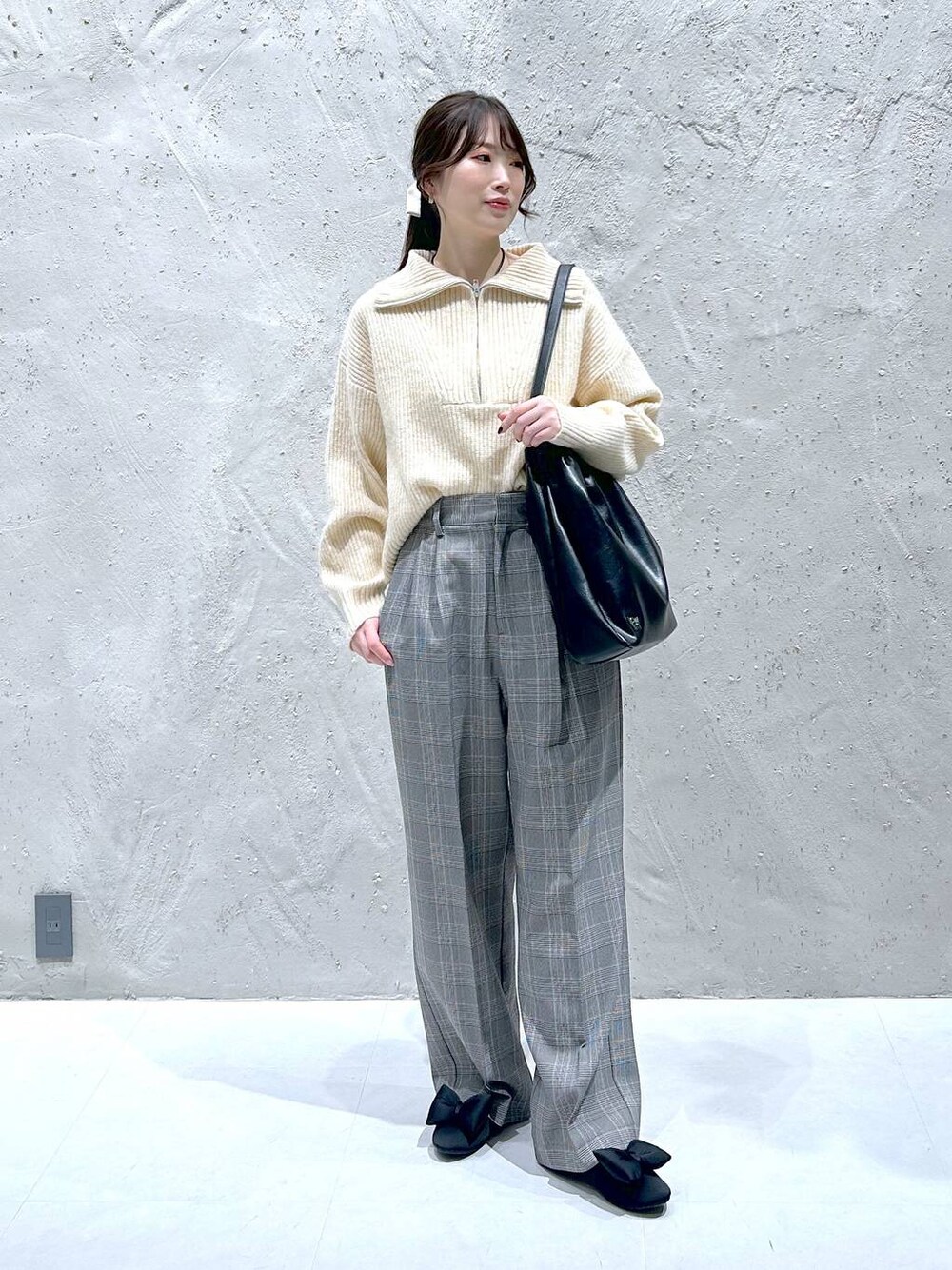 ブラック系のショルダーバッグ、グレー系のスラックス、ホワイト系のニット/セーターを着用したレディースの冬コーディネートの1枚目の写真