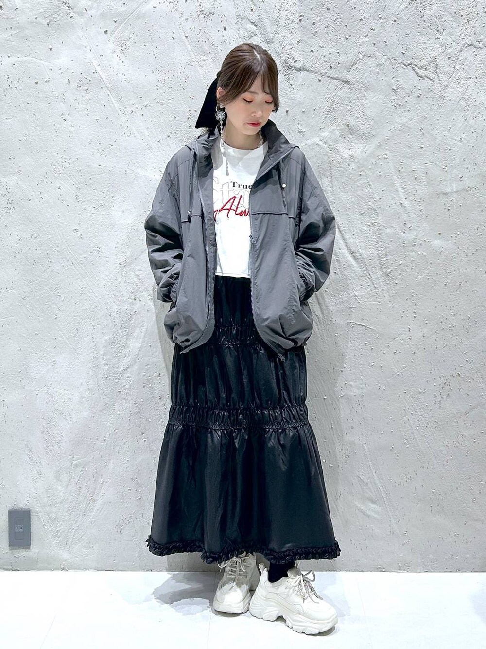 ブラック系のスカート、ホワイト系のスニーカー、ホワイト系のTシャツ/カットソーを着用したレディースの秋コーディネートの1枚目の写真