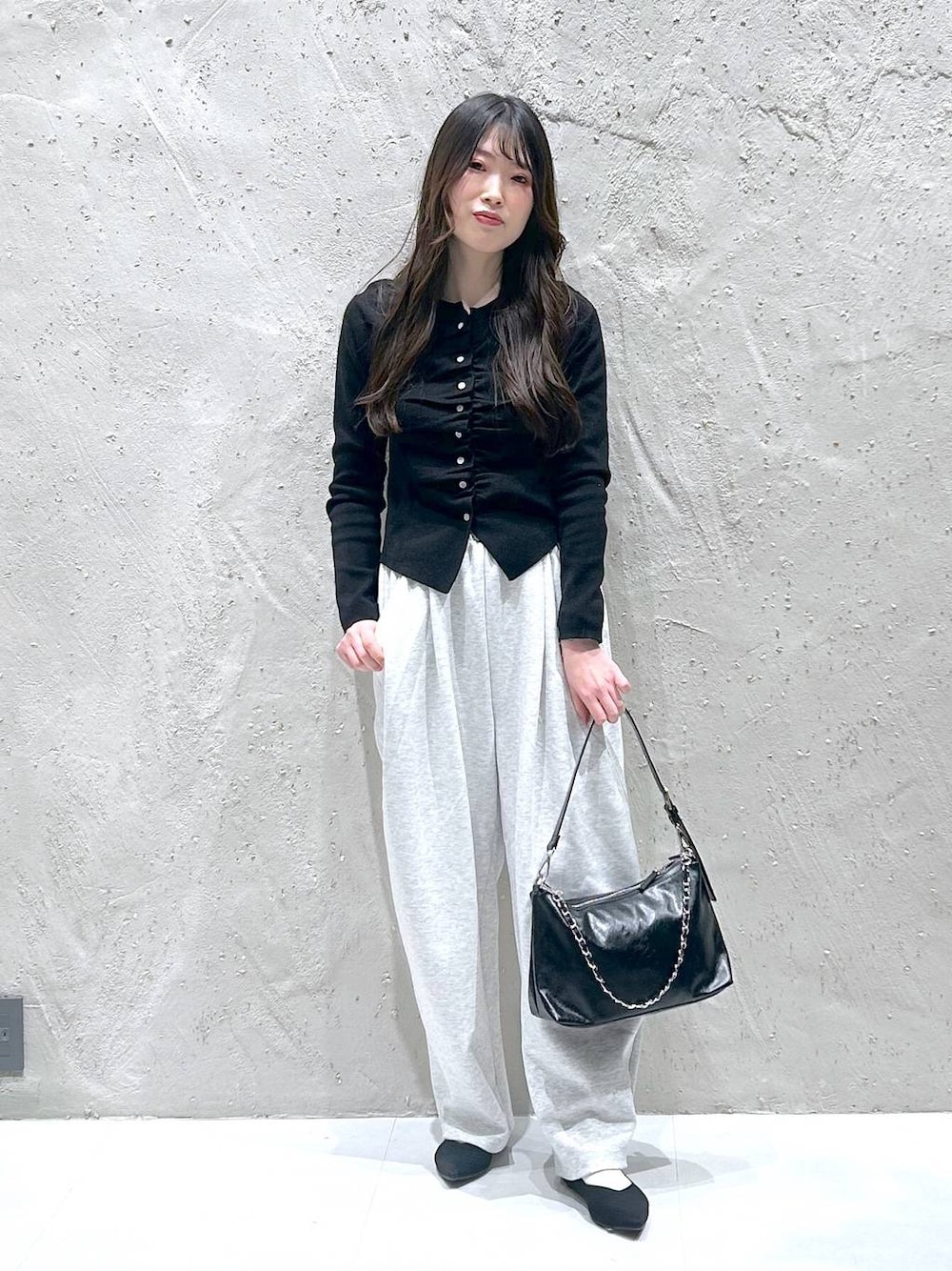 グレー系のスウェットパンツ、ブラック系のショルダーバッグ、ブラック系のパンプスを着用したレディースの春コーディネートの1枚目の写真