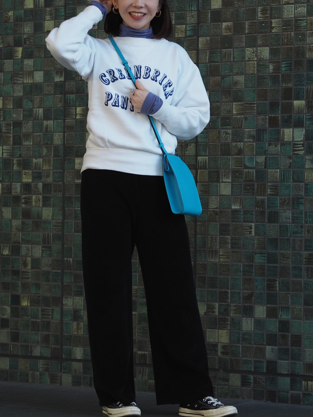 ブラック系のスニーカー、ブルー系のショルダーバッグ、ホワイト系のスウェットを着用したレディースの冬コーディネートの1枚目の写真