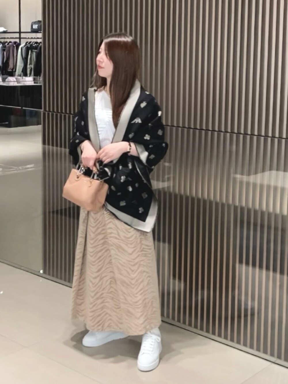 ホワイト系のTシャツ/カットソー、ブラック系のハンドバッグ、ブラック系のストール/ショールを着用したレディースの秋コーディネートの1枚目の写真