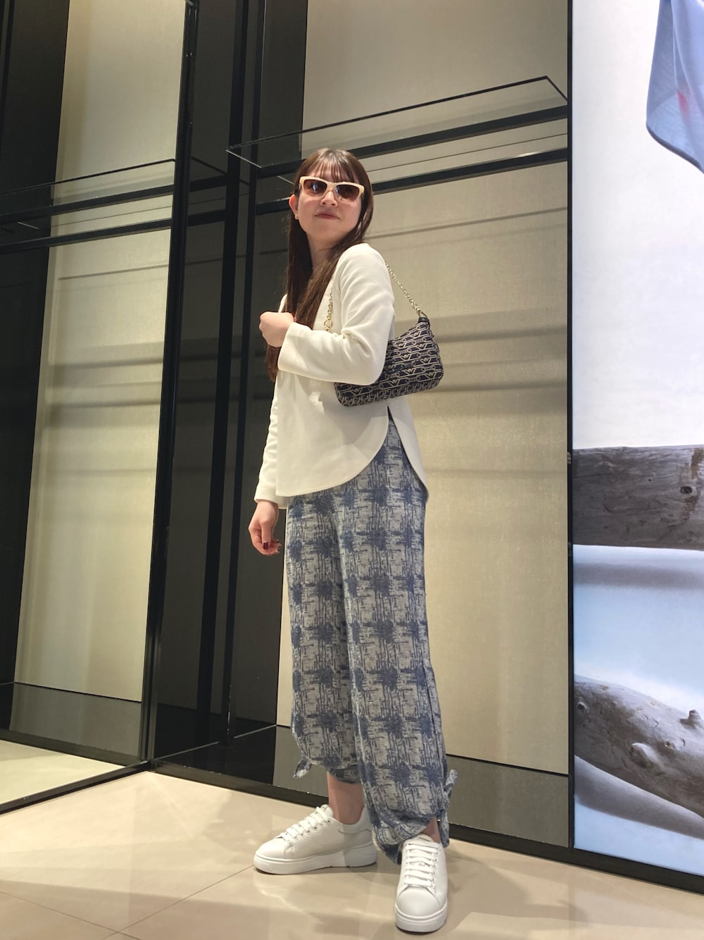 ブルー系のショルダーバッグ、ホワイト系のニット/セーター、ブルー系のその他パンツを着用したレディースの冬コーディネートの1枚目の写真