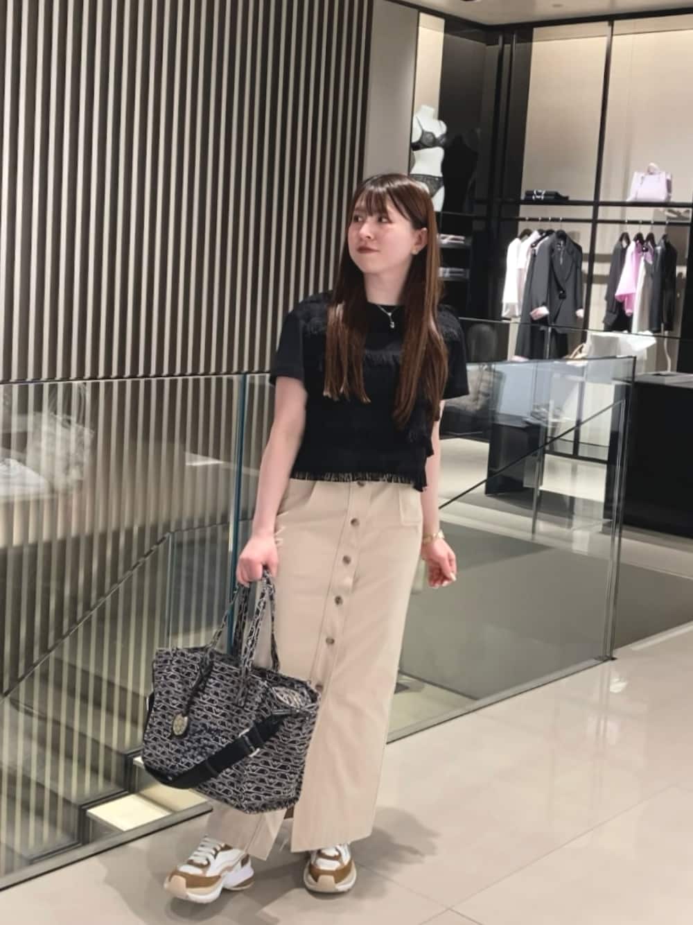 ブルー系のトートバッグ、ホワイト系のTシャツ/カットソー、ベージュ系のスカートを着用したレディースの冬コーディネートの1枚目の写真