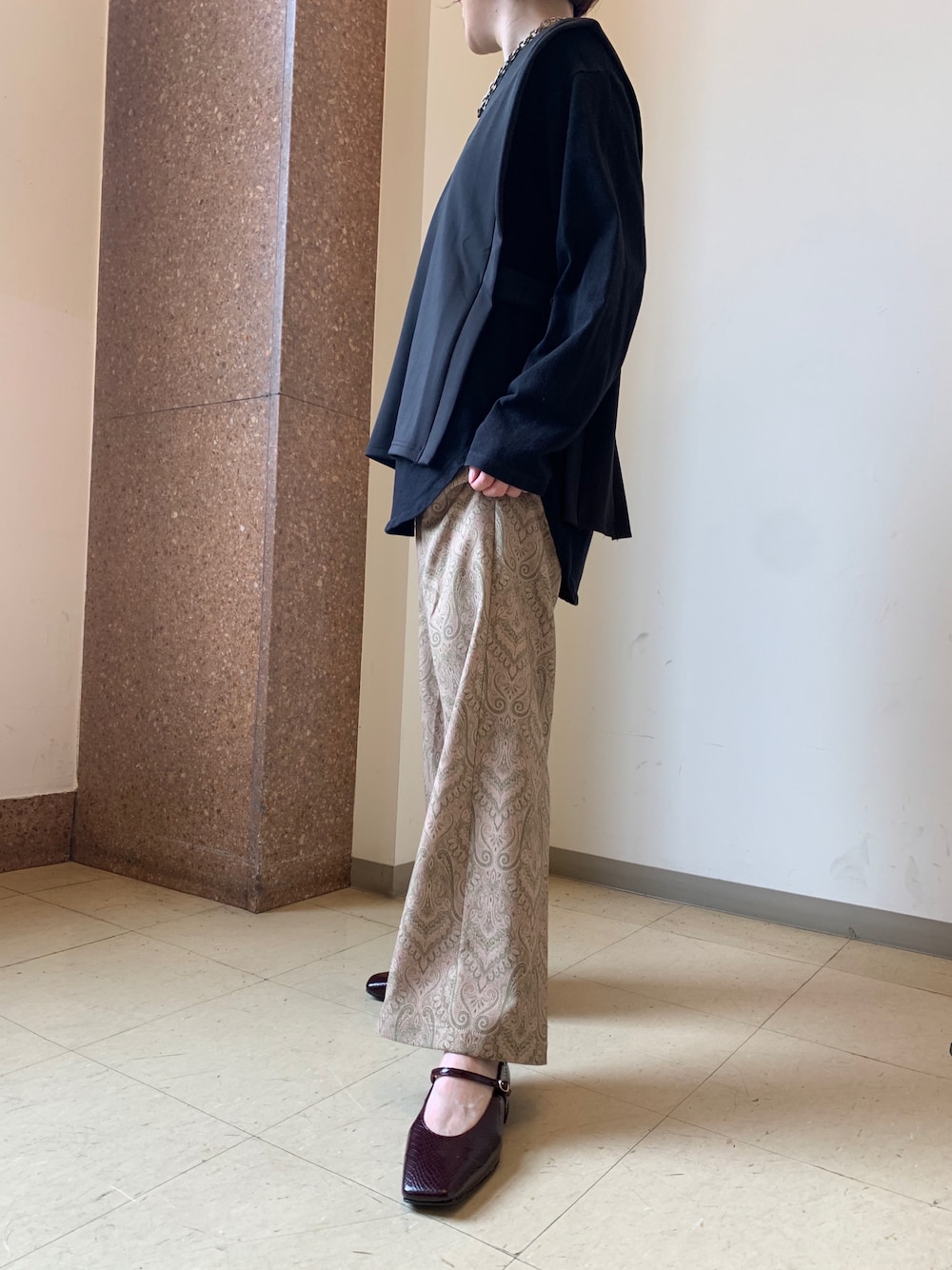 レッド系のパンプス、ベージュ系のスラックスを着用したレディースの秋コーディネートの1枚目の写真