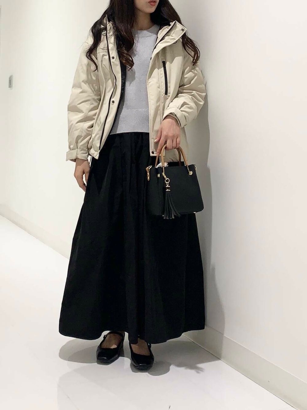 ブラック系のトートバッグ、ベージュ系のダウンジャケット/コート、ブルー系のニット/セーターを着用したレディースの冬コーディネートの1枚目の写真