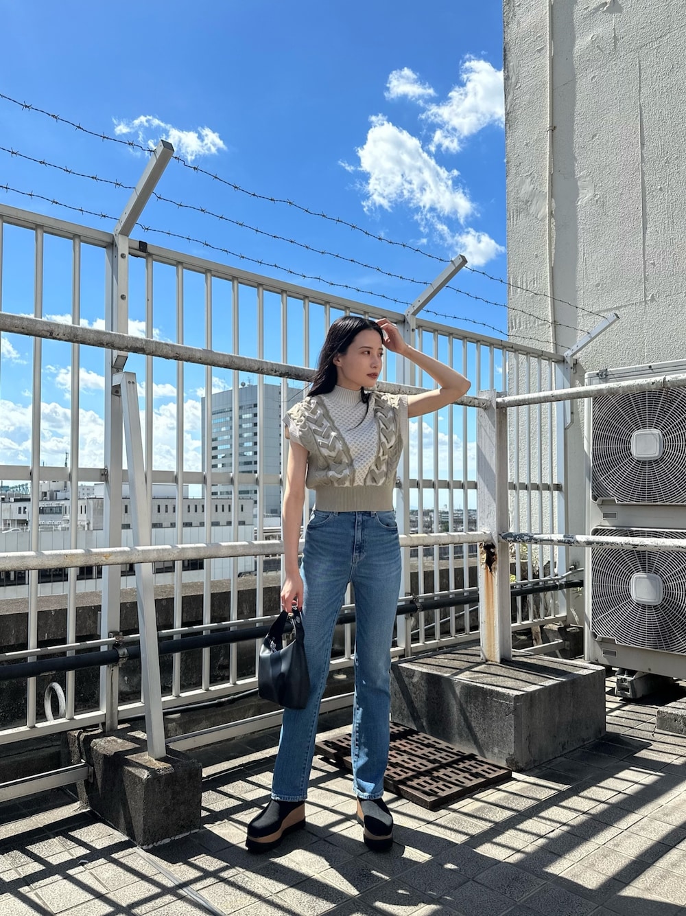 ホワイト系のニット/セーター、ブルー系のデニムパンツ、ブラック系のブーツを着用したレディースの夏コーディネートの1枚目の写真