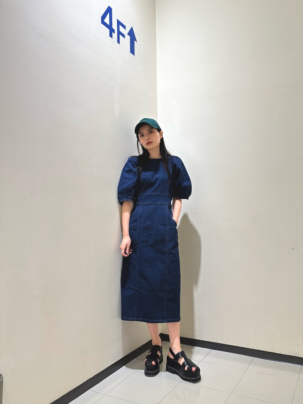 ブルー系のワンピース、ブラック系のサンダル、グリーン系のキャップを着用したレディースの春コーディネートの1枚目の写真