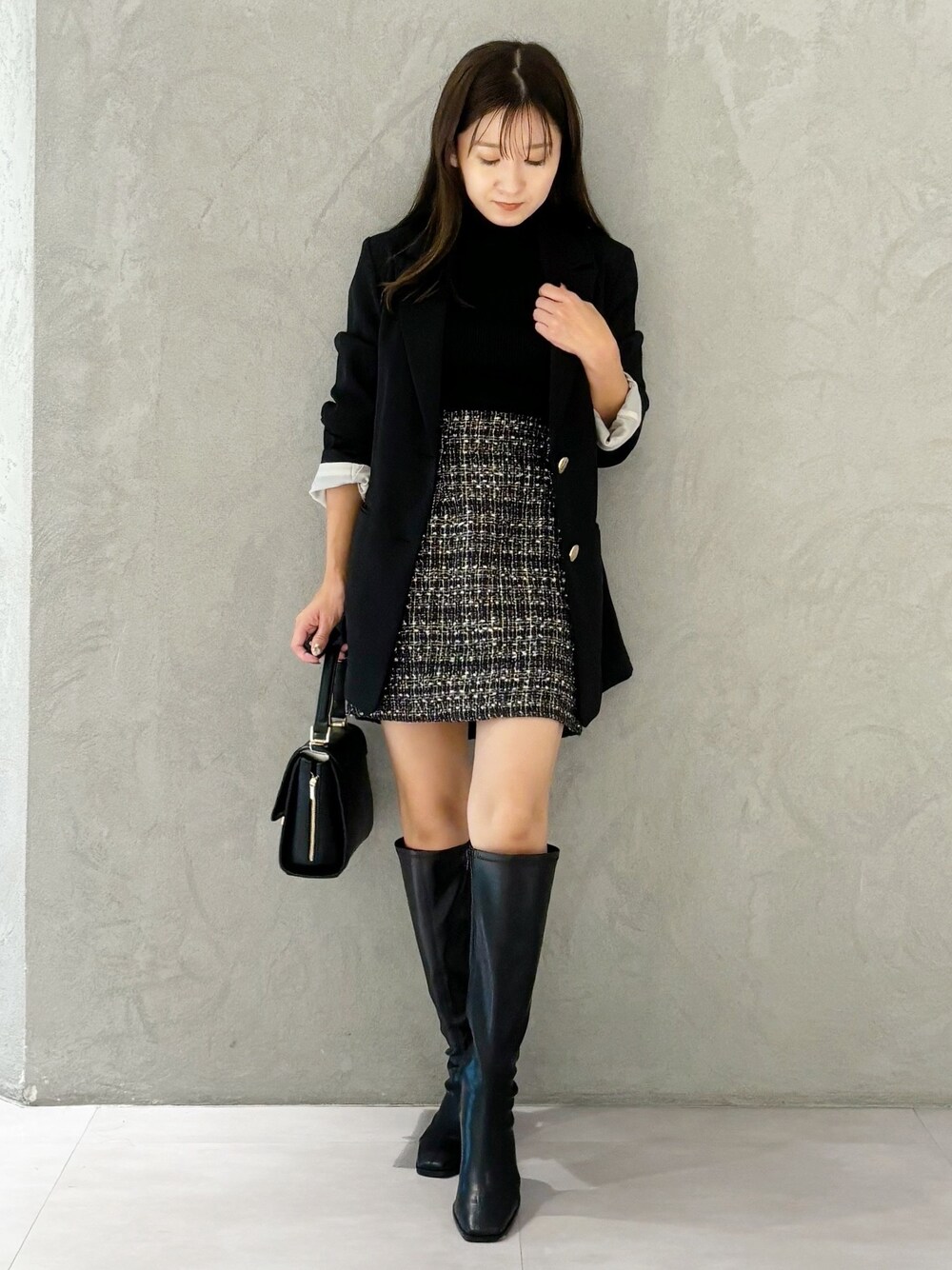 ブラック系のスカート、ブラック系のブーツ、ブラック系のショルダーバッグを着用したレディースの秋コーディネートの1枚目の写真