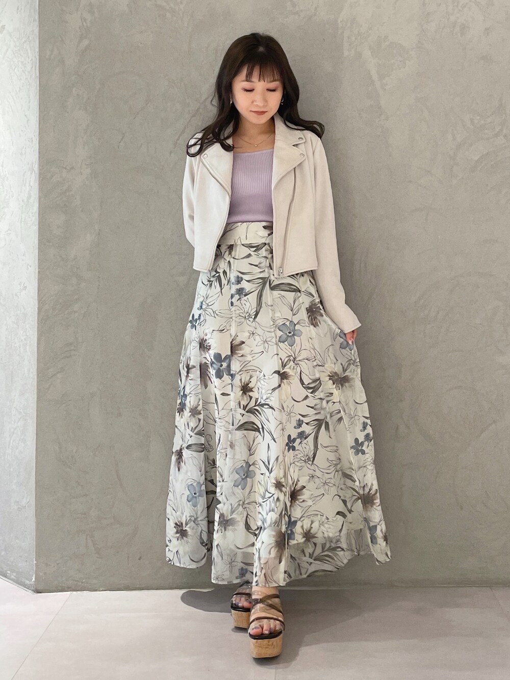 グリーン系のスカート、ピンク系のライダースジャケット、ブラック系のサンダルを着用したレディースの春コーディネートの1枚目の写真