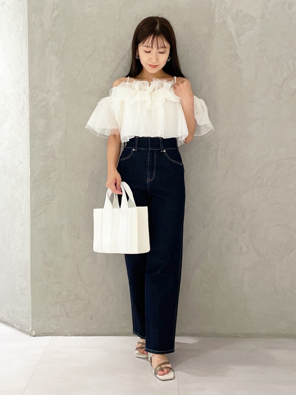 ピンク系のトートバッグ、ブルー系のデニムパンツ、ホワイト系のサンダルを着用したレディースの夏コーディネートの1枚目の写真