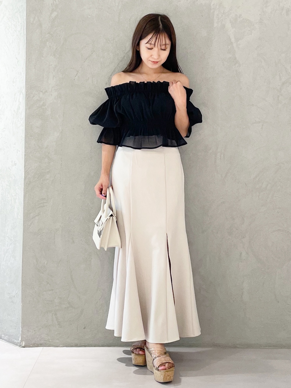 ホワイト系のスカート、ブラウン系のサンダル、ベージュ系のショルダーバッグを着用したレディースの夏コーディネートの1枚目の写真