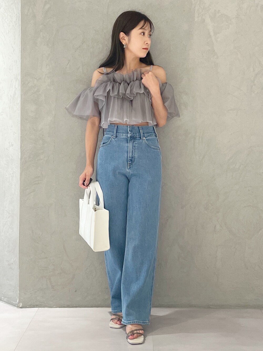 ブルー系のデニムパンツ、ホワイト系のサンダル、ホワイト系のトートバッグを着用したレディースの夏コーディネートの1枚目の写真