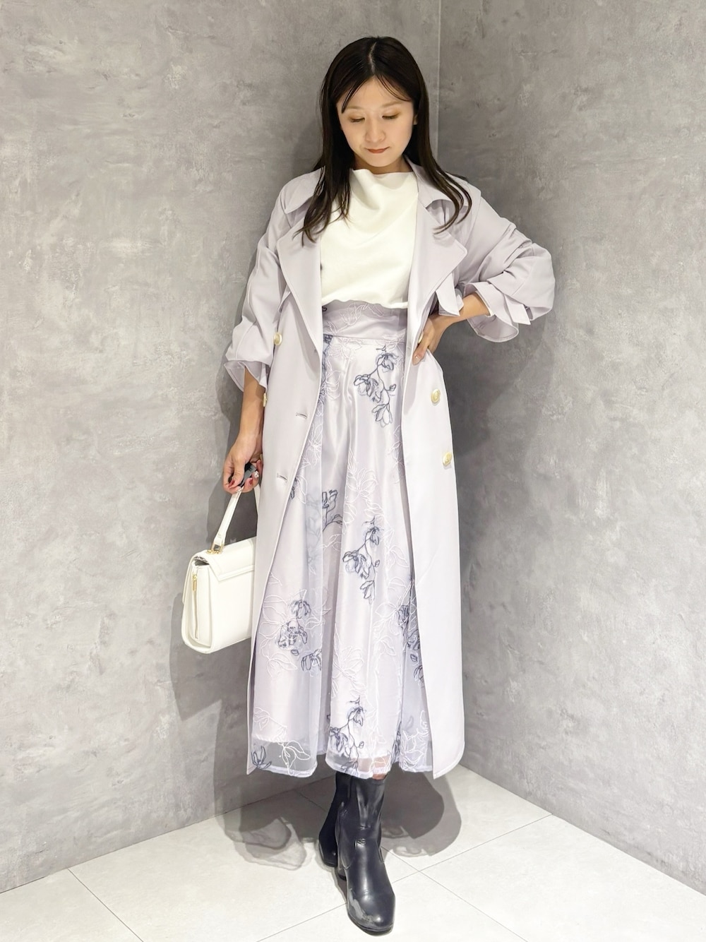 パープル系のスカート、ブラック系のブーツ、ホワイト系のハンドバッグを着用したレディースの冬コーディネートの1枚目の写真