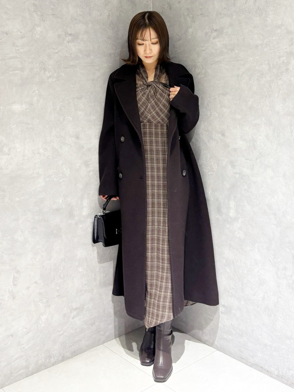 ブラウン系のチェスターコート、ブラウン系のワンピース、ブラウン系のブーツを着用したレディースの冬コーディネートの1枚目の写真