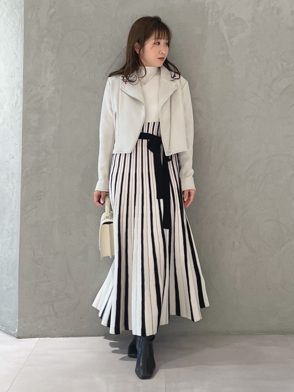 ホワイト系のワンピース、ピンク系のライダースジャケット、ホワイト系のハンドバッグを着用したレディースの春コーディネートの1枚目の写真