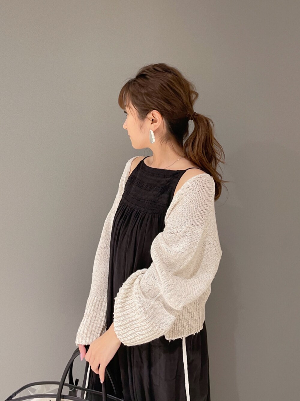 ブラック系のトートバッグ、ブラック系のワンピース、ブラウン系のサンダルを着用したレディースの春コーディネートの1枚目の写真