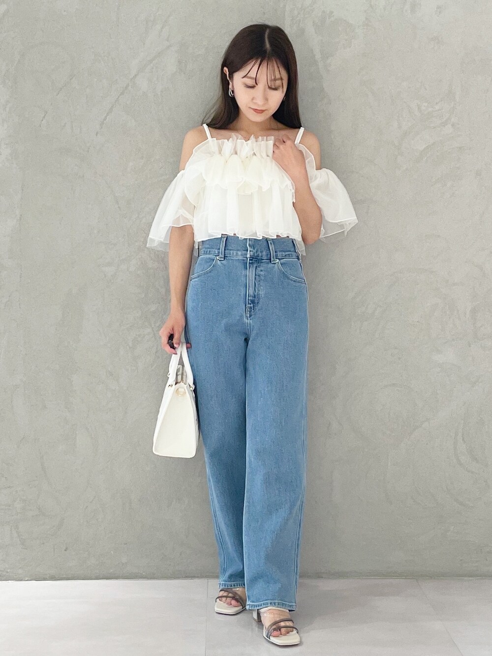 ブルー系のデニムパンツ、ホワイト系のショルダーバッグ、ホワイト系のサンダルを着用したレディースの夏コーディネートの1枚目の写真