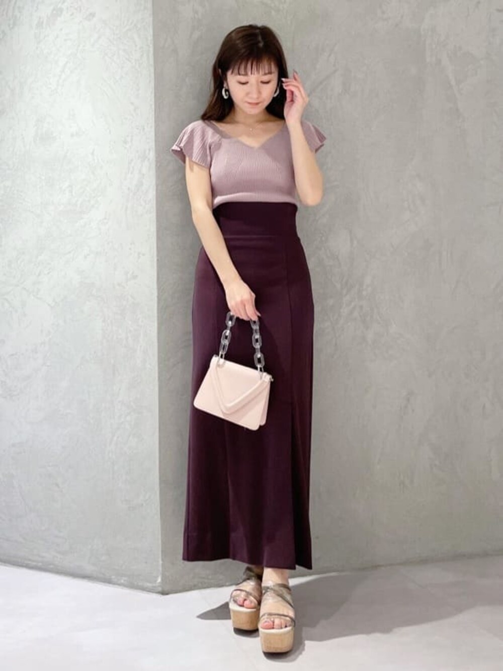 ピンク系のショルダーバッグ、ピンク系のニット/セーター、グリーン系のサンダルを着用したレディースの春コーディネートの1枚目の写真