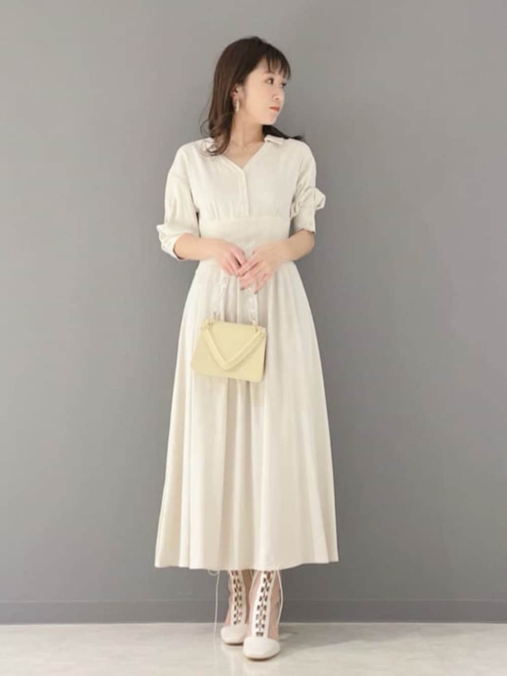 ベージュ系のワンピース、イエロー系のショルダーバッグ、ホワイト系のその他シューズを着用したレディースの春コーディネートの1枚目の写真