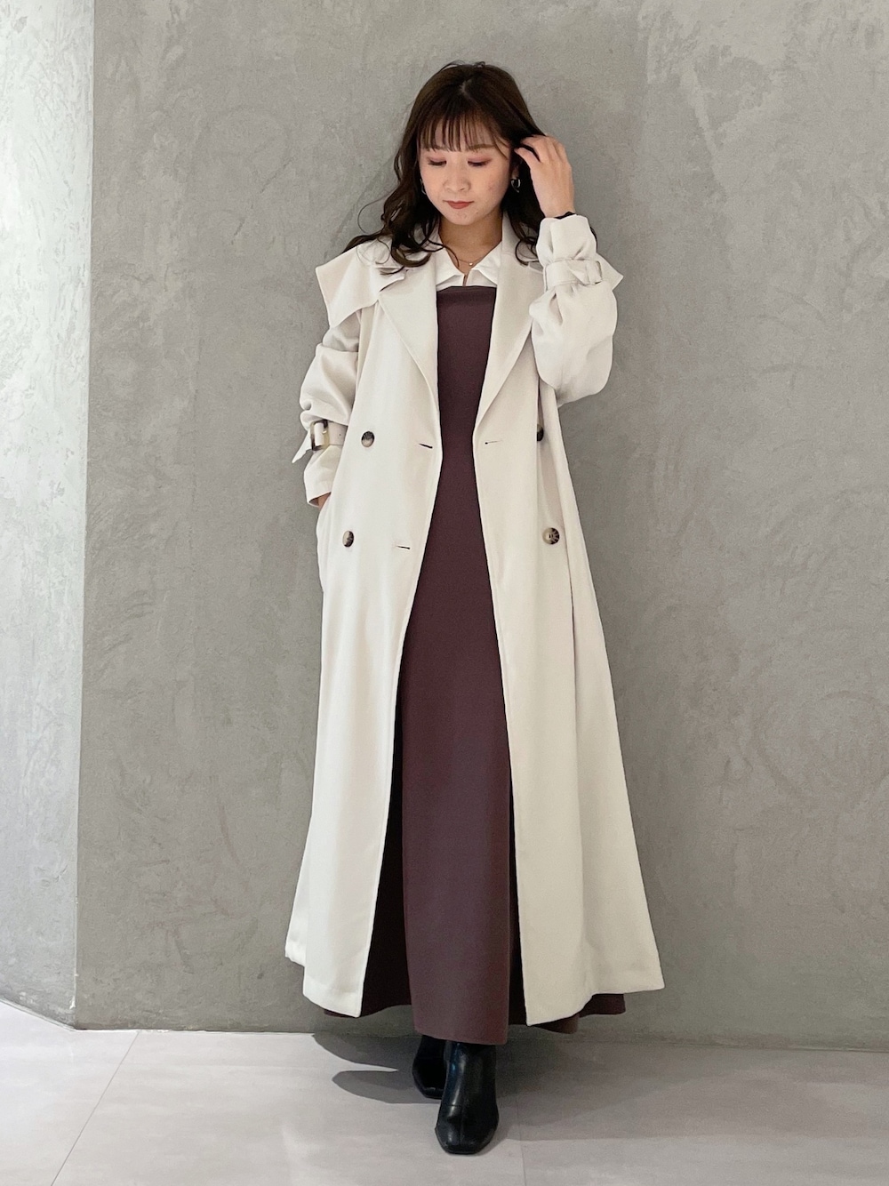 パープル系のワンピース、ブラック系のブーツ、ホワイト系のトレンチコートを着用したレディースの冬コーディネートの1枚目の写真