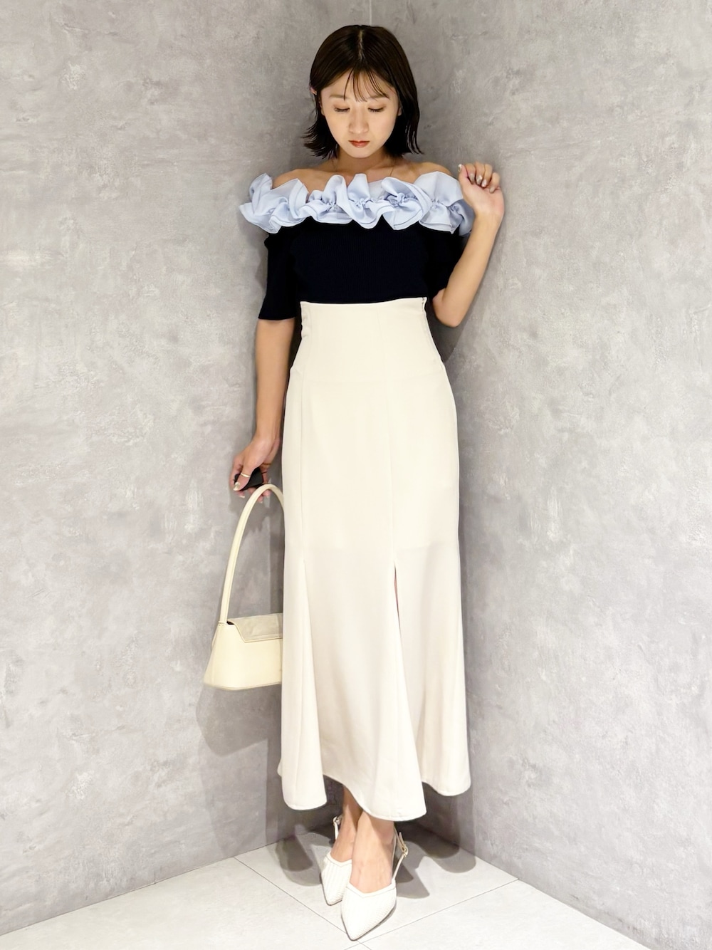 ホワイト系のスカート、ホワイト系のパンプス、ブルー系のニット/セーターを着用したレディースの春コーディネートの1枚目の写真