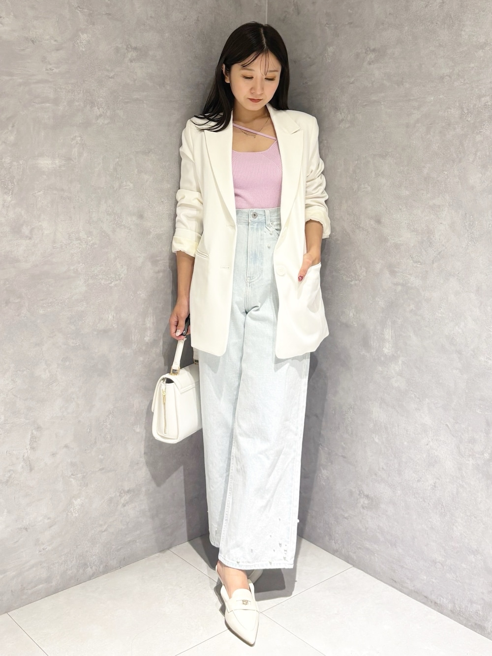 ブルー系のデニムパンツ、ホワイト系のパンプス、ホワイト系のハンドバッグを着用したレディースの冬コーディネートの1枚目の写真