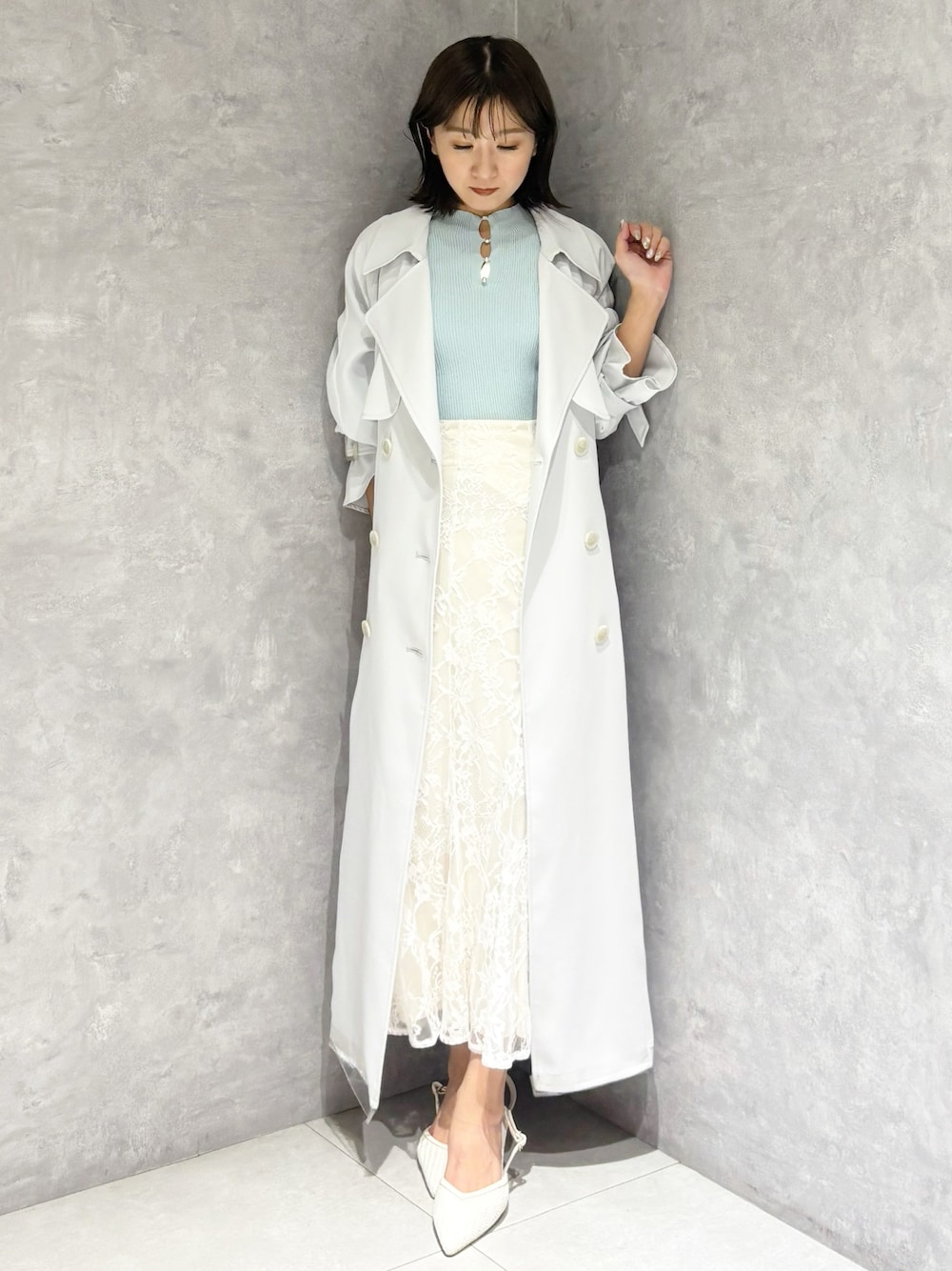 ホワイト系のスカート、ブルー系のトレンチコート、グリーン系のニット/セーターを着用したレディースの春コーディネートの1枚目の写真