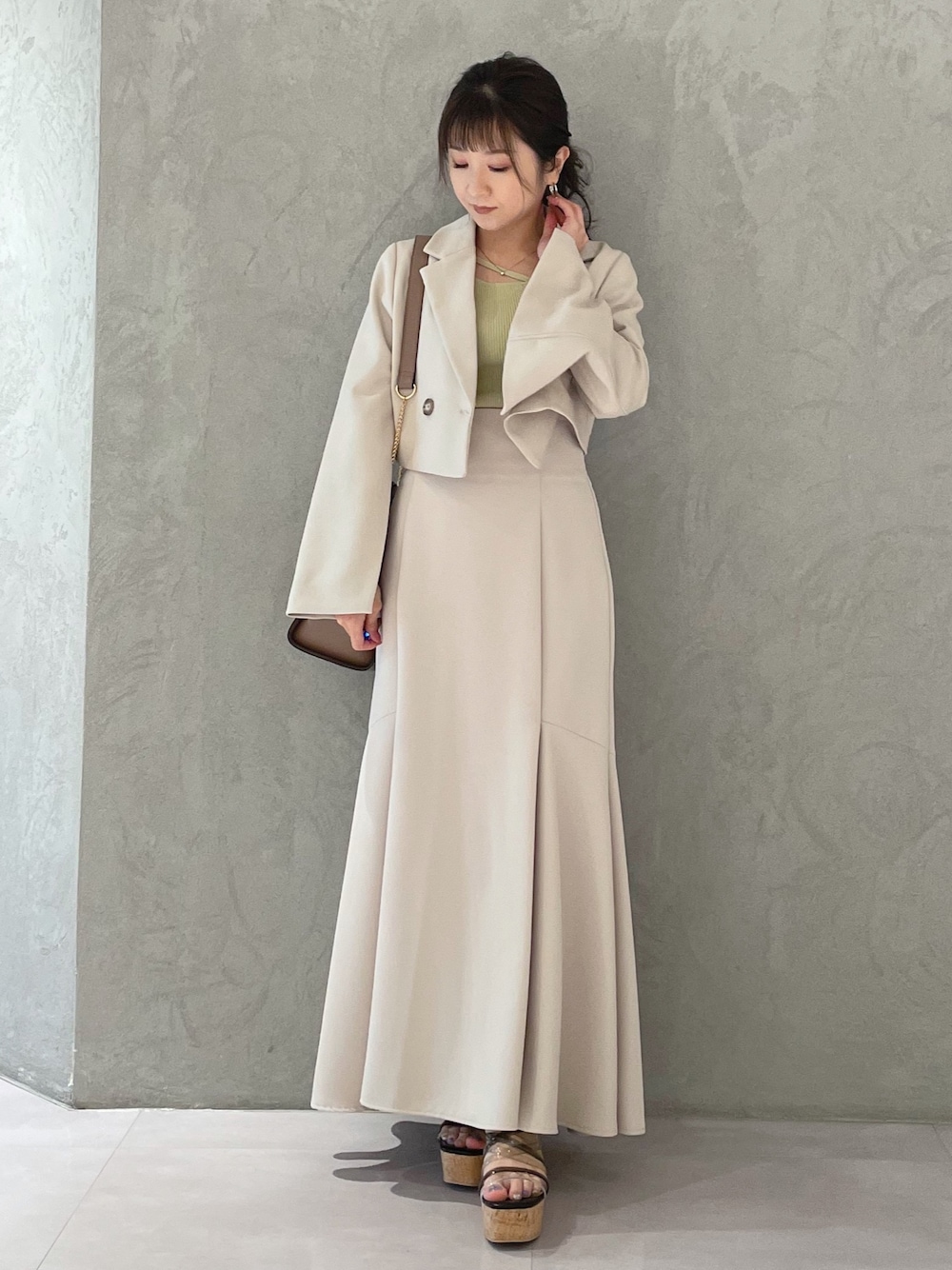 ブラック系のサンダル、ベージュ系のスカート、イエロー系のニット/セーターを着用したレディースの春コーディネートの1枚目の写真