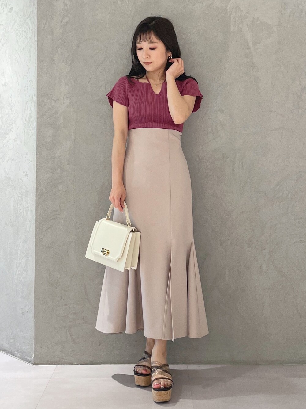 ブラック系のサンダル、ホワイト系のハンドバッグ、ピンク系のスカートを着用したレディースの春コーディネートの1枚目の写真