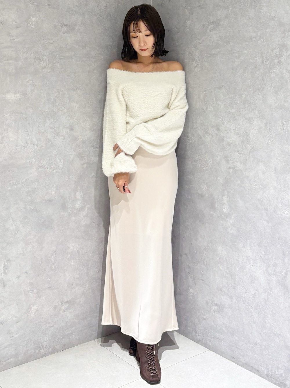 ピンク系のスカート、ホワイト系のニット/セーター、ブラウン系のブーツを着用したレディースの秋コーディネートの1枚目の写真