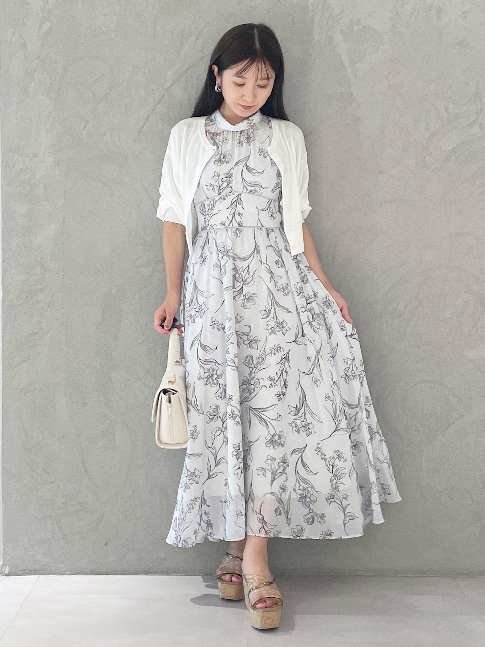 グレー系のワンピース、ブラウン系のサンダル、ホワイト系のショルダーバッグを着用したレディースの夏コーディネートの1枚目の写真