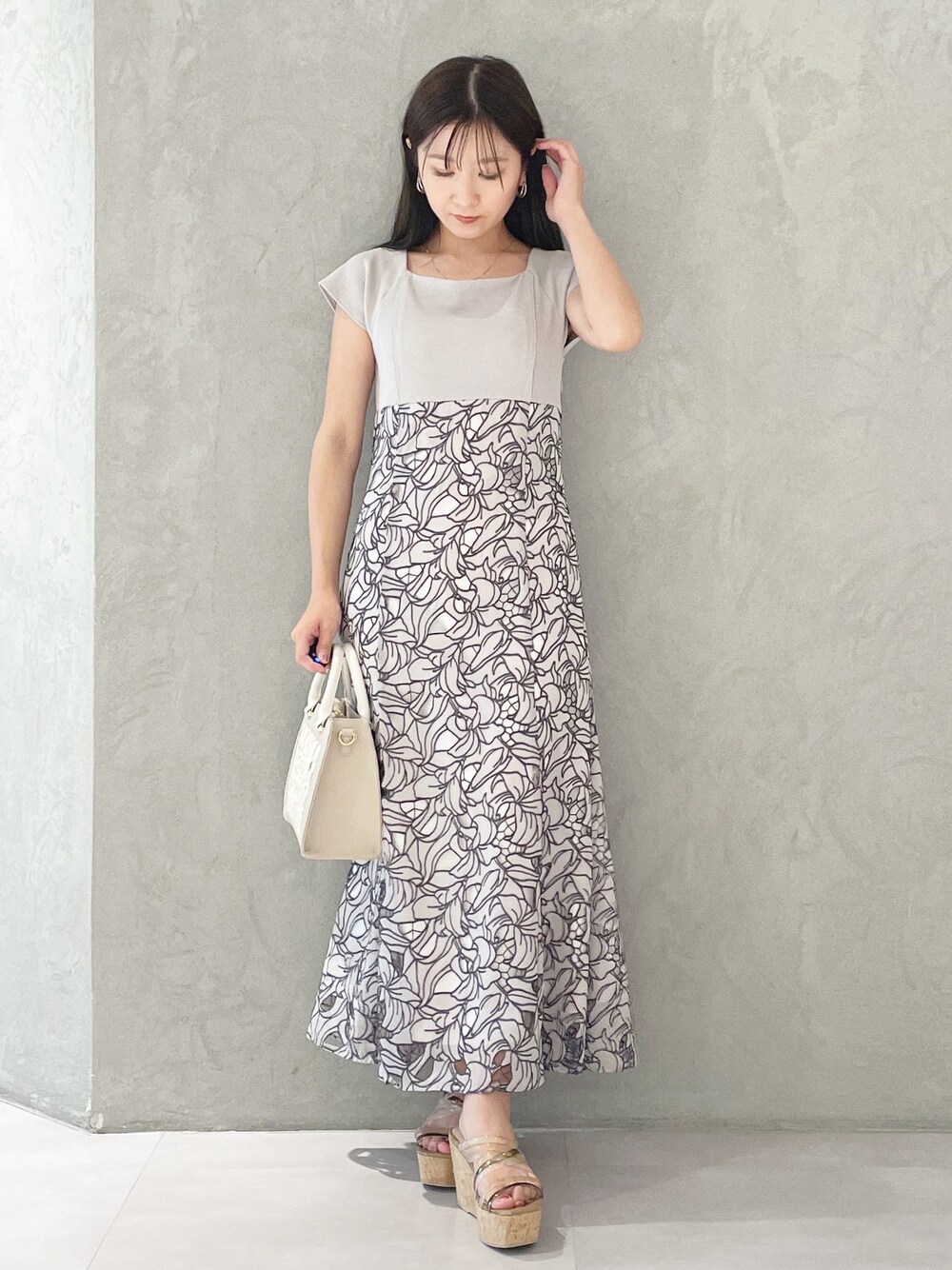 ホワイト系のショルダーバッグ、ブラウン系のサンダル、ベージュ系のワンピースを着用したレディースの春コーディネートの1枚目の写真