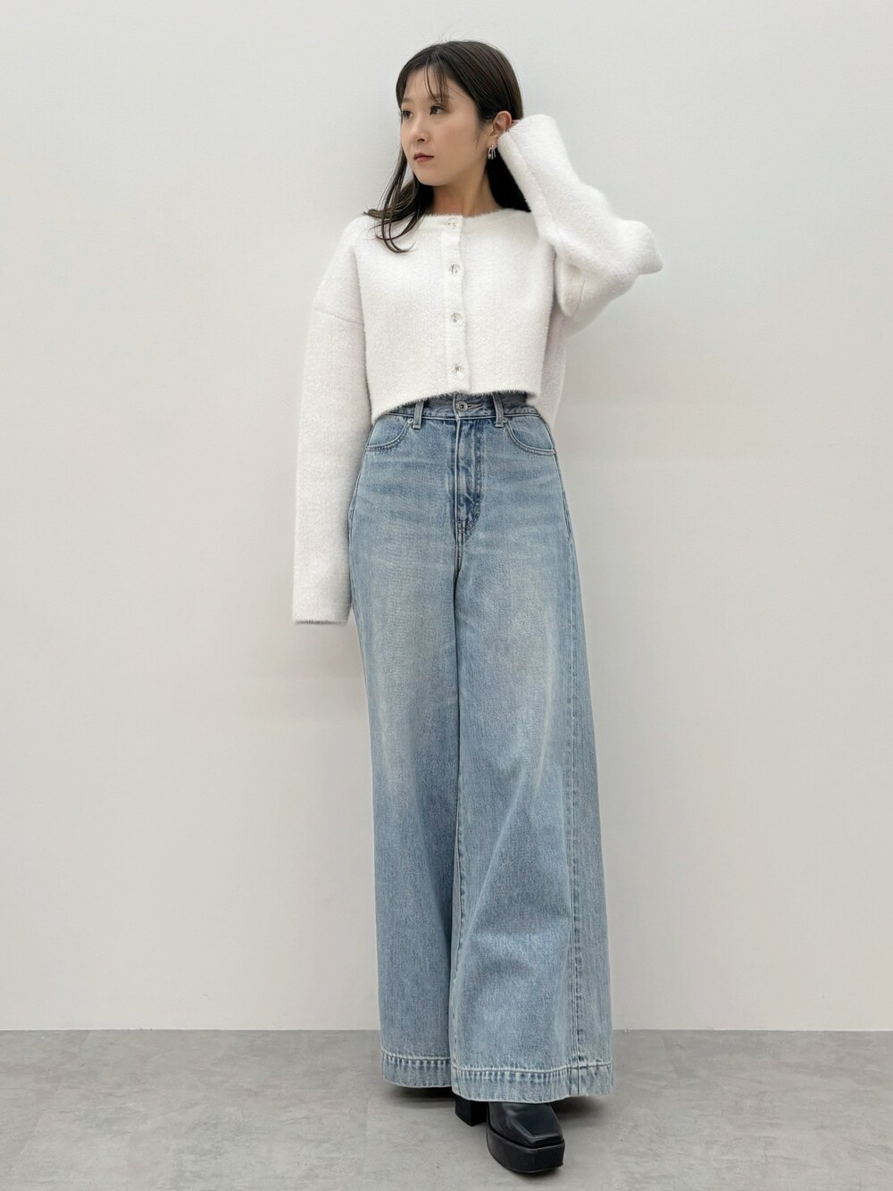 ブルー系のデニムパンツ、ブラック系のブーツ、ホワイト系のカーディガン/ボレロを着用したレディースの秋コーディネートの1枚目の写真
