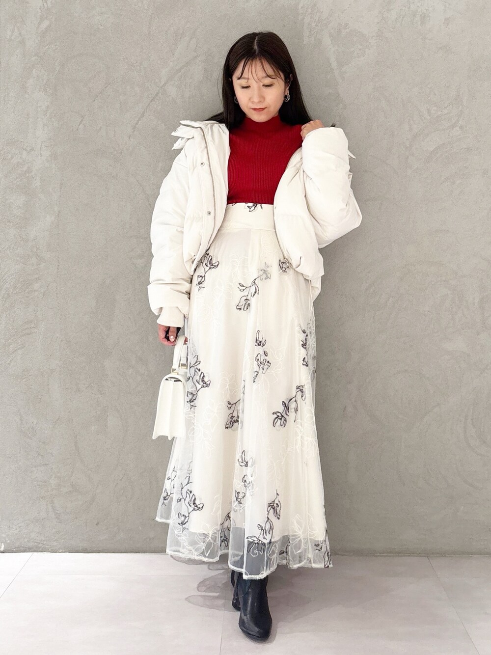 ホワイト系のスカート、ブラック系のブーツ、ホワイト系のハンドバッグを着用したレディースの冬コーディネートの1枚目の写真