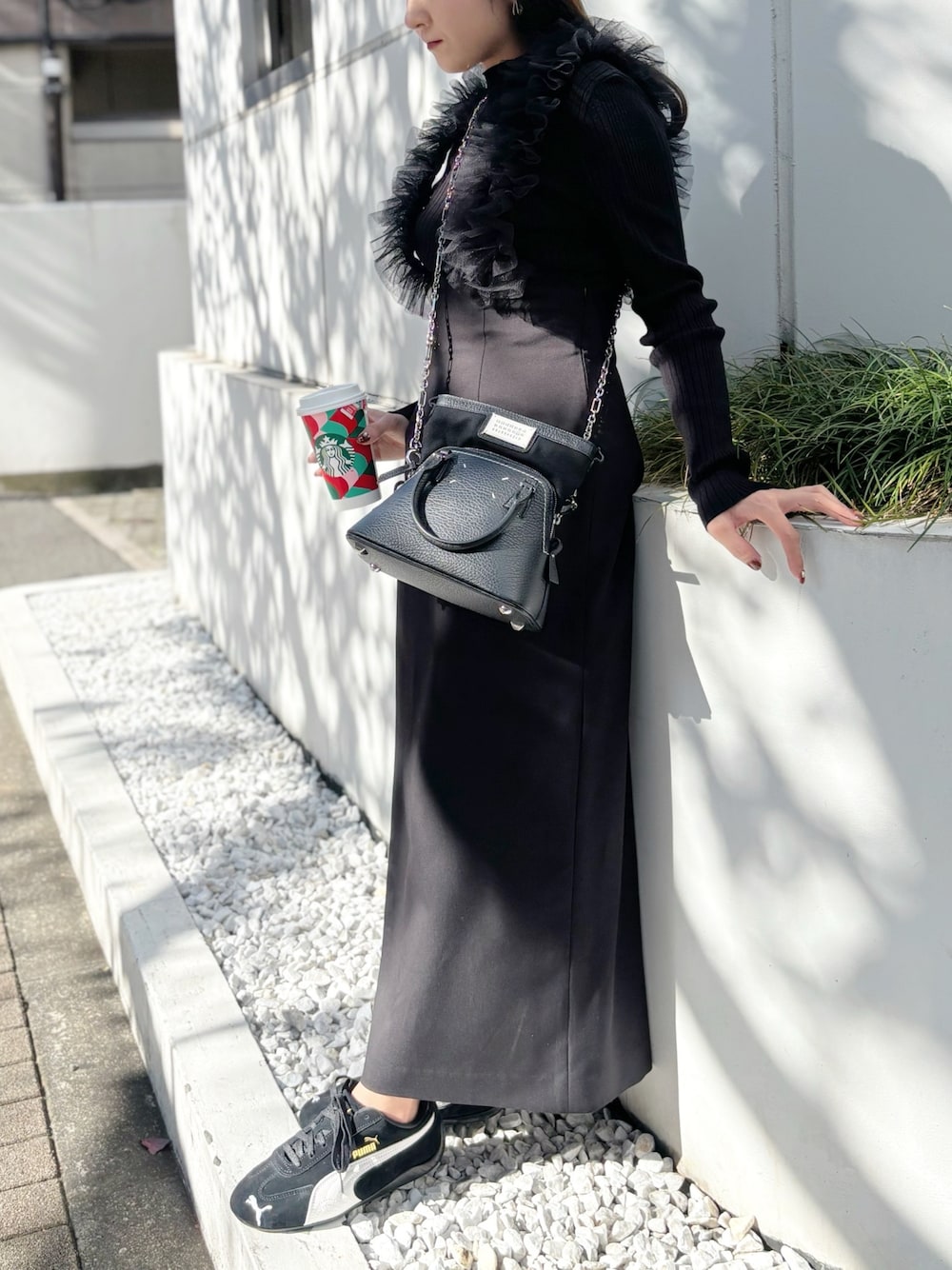 ブラック系のスカート、ブラック系のスニーカー、グレー系のニット/セーターを着用したレディースの秋コーディネートの1枚目の写真