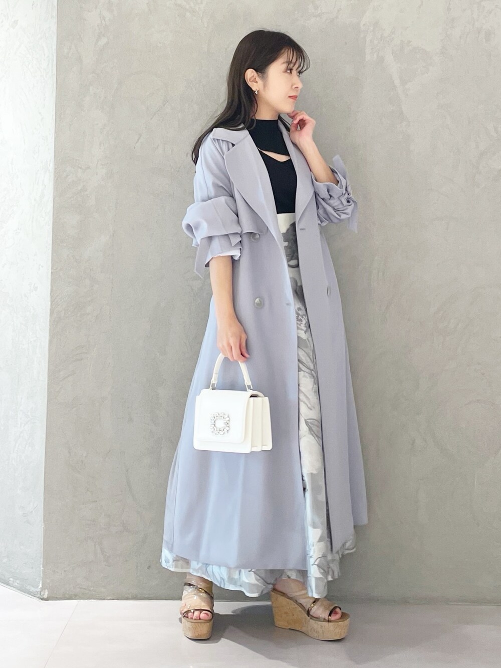 ブルー系のトレンチコート、ブラウン系のサンダル、ホワイト系のショルダーバッグを着用したレディースの春コーディネートの1枚目の写真