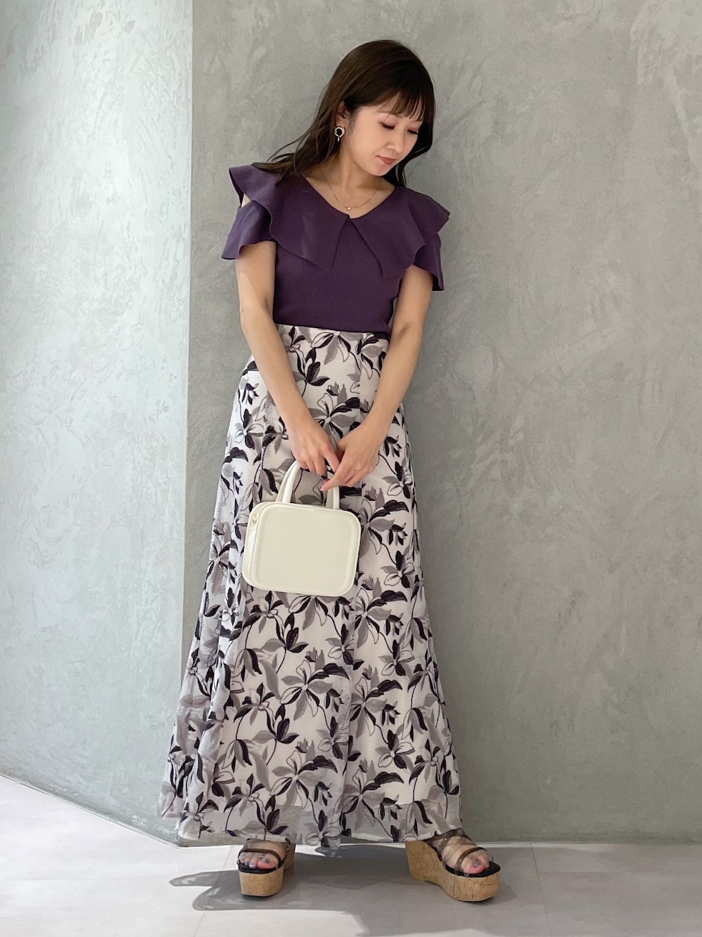 ホワイト系のハンドバッグ、ブラック系のサンダル、パープル系のニット/セーターを着用したレディースの春コーディネートの1枚目の写真