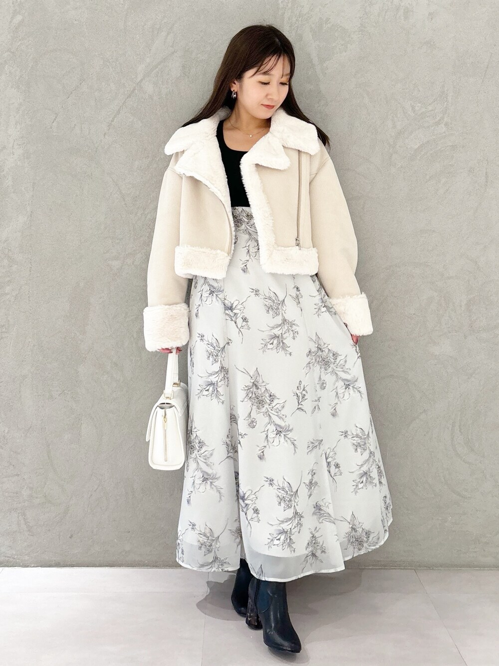 ブラック系のワンピース、ブラック系のブーツ、ホワイト系のハンドバッグを着用したレディースの秋コーディネートの1枚目の写真